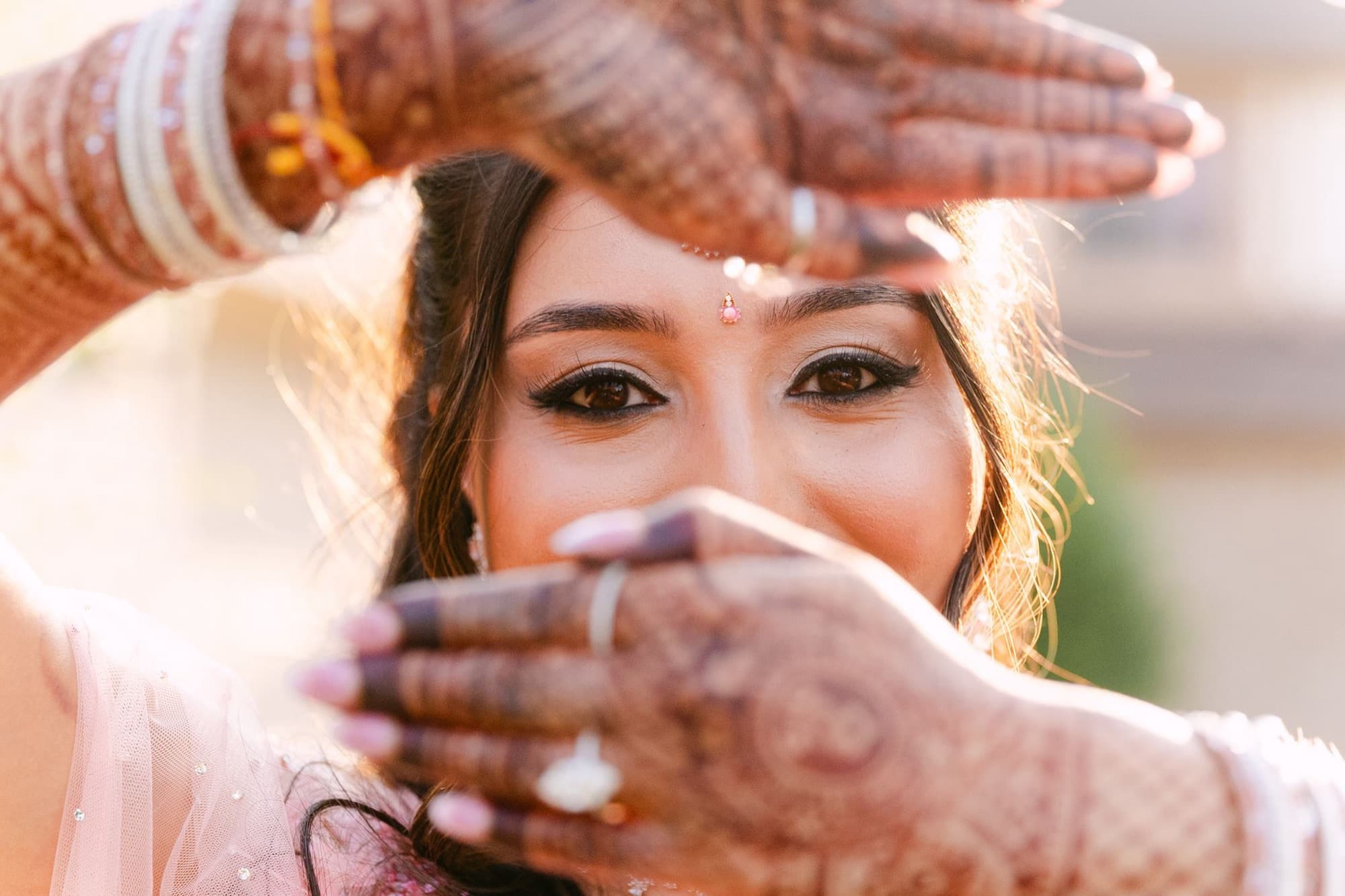 Bride's eyes framed by the veil and mehndi hands, Toronto