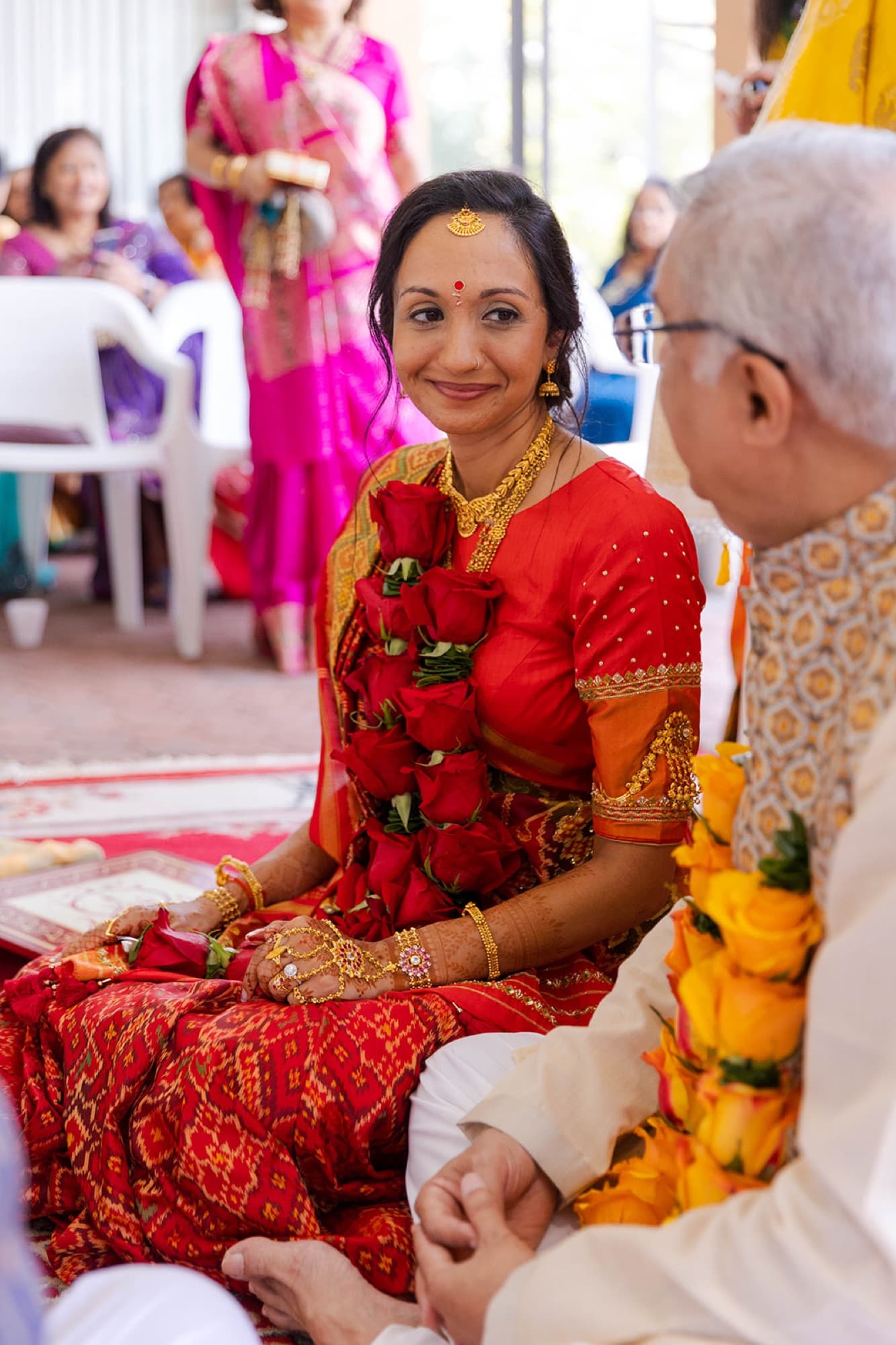 Bride in red with a rose garland during the haldi, Toronto