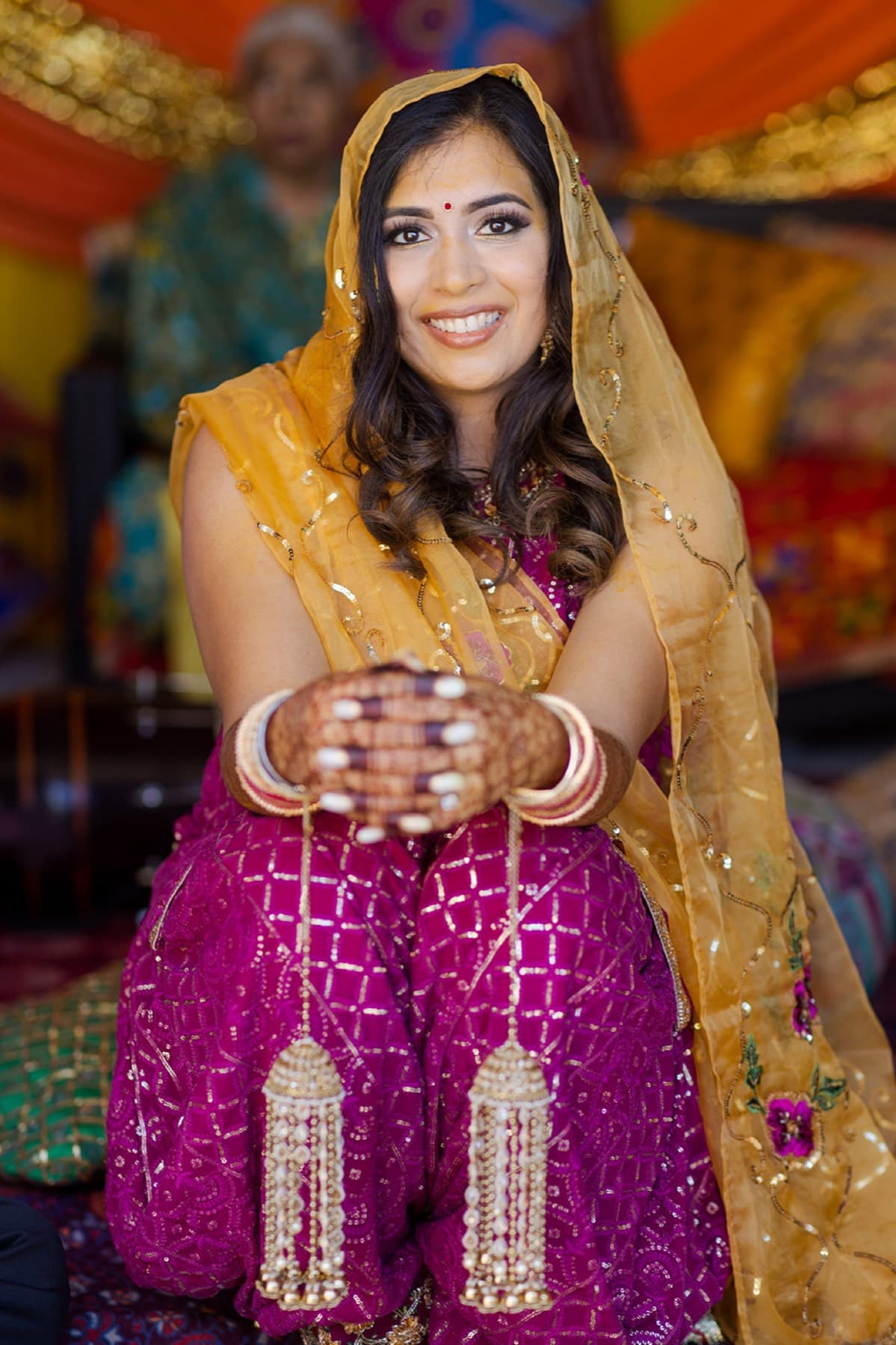 Bride's mehndi-covered hands cupped in her yellow dupatta at the haldi, Toronto