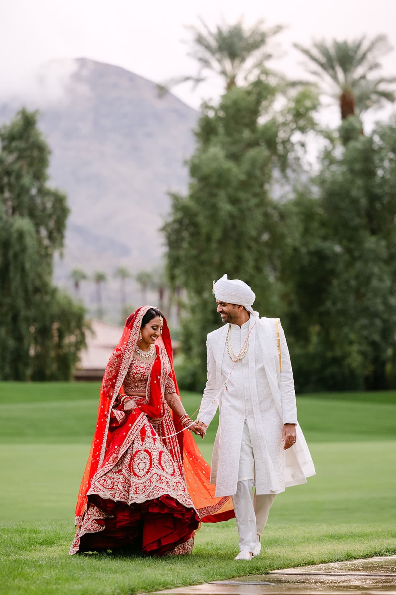 Bride and groom in red lehenga and sherwani walking the grounds, GTA South Asian wedding