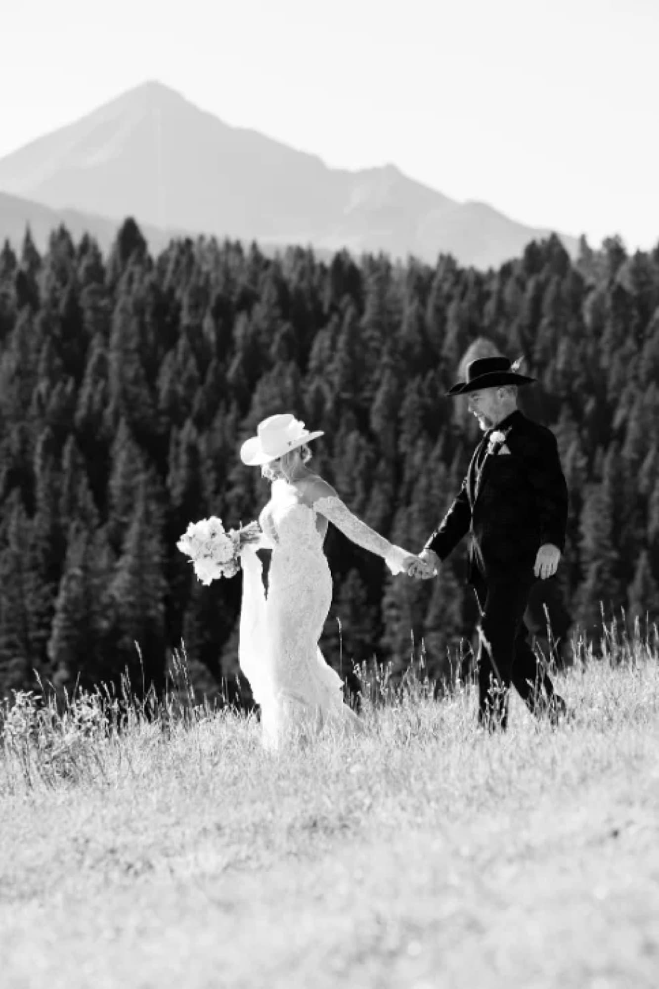 Couple walking the hillside hand in hand, black and white, editorial wedding