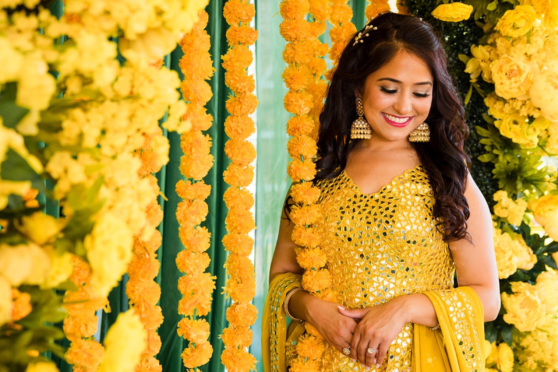 Bride's mehndi-covered hands cupped in her yellow dupatta at the haldi, Toronto