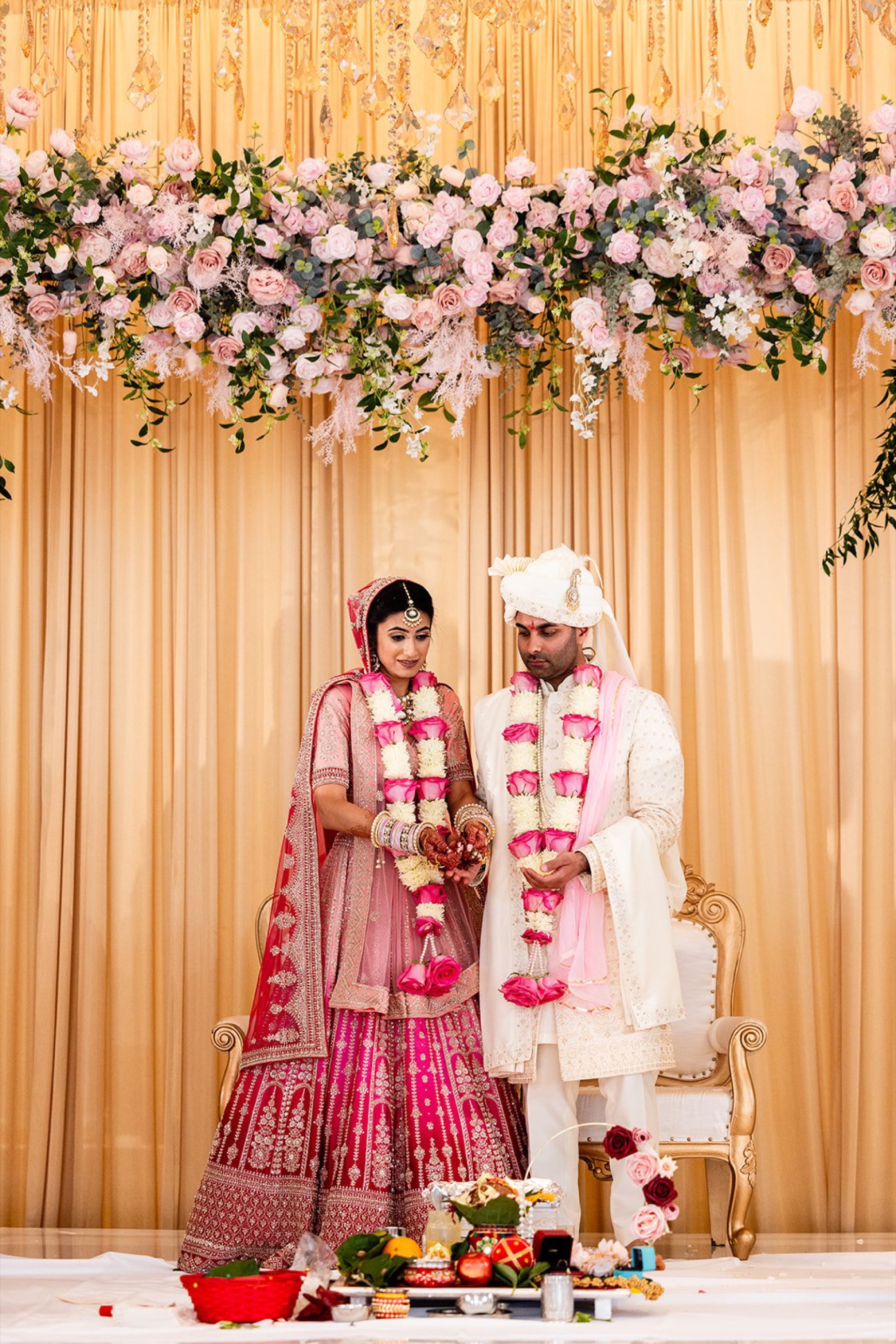Bride and groom exchange garlands during a Hindu wedding ceremony in warm candlelight, Toronto wedding photography